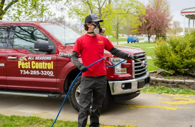 all seasons exterminator spraying the perimeter of a home